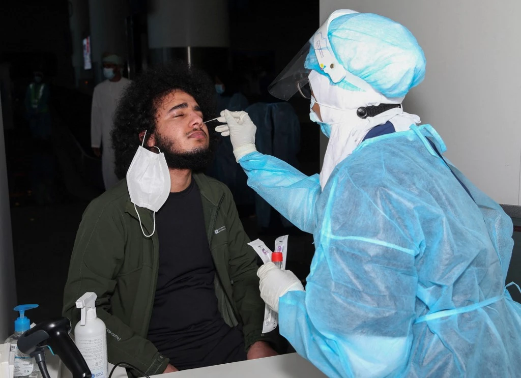 A medical worker collects a swab sample from a passenger for a RT-PCR test at the Muscat international airport in the Omani capital on Oct. 1, 2020. (File/AFP)