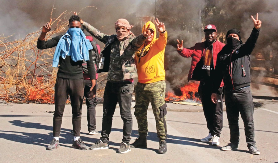 Protesters flash victory sign as youths burn tires and block roads in the southern Tunisian city of Tataouine during Friday’s demonstration. (AFP)