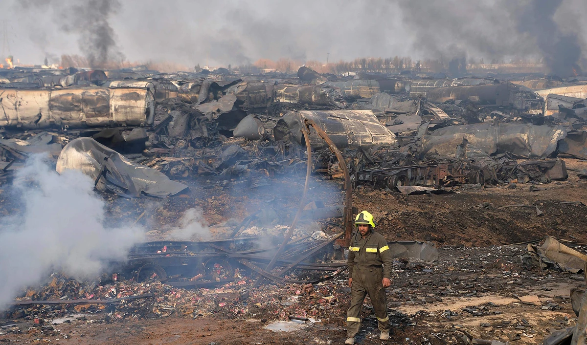 A firefighter walks amidst wreckage of gas tankers after a fire accident at Islam Qala on the outskirts of Herat, in the border between Afghanistan and Iran on February 14, 2021. (AFP)