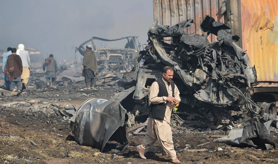 Afghan men walks past the wreckage of gas tankers after a fire accident at Islam Qala on the outskirts of Herat, in the border between Afghanistan and Iran on February 14, 2021. (AFP)