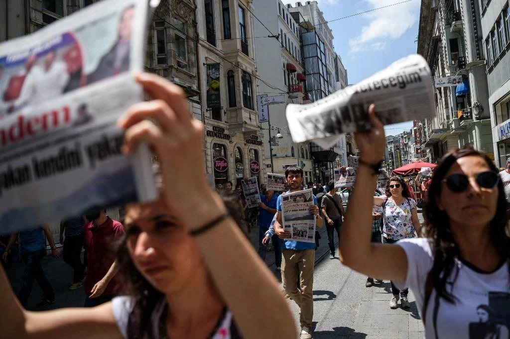 Demonstrators hold copies of pro-Kurdish newspaper Ozgur Gundem as they a protest against the arrest of three prominent activists for press freedom on June 25, 2016 in Istanbul. (AFP)