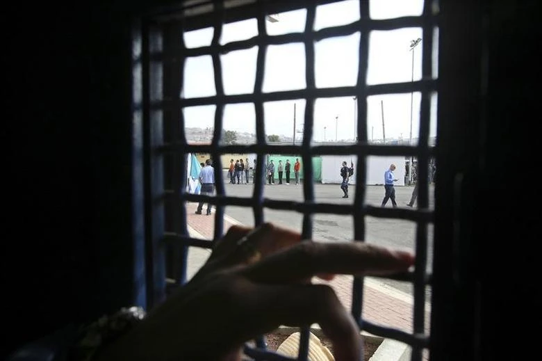 n Israeli prison guard stands by a window as Palestinians prisoners wait in line before their release from Ofer prison outside the West Bank city of Ramallah December 15, 2008. (Reuters)