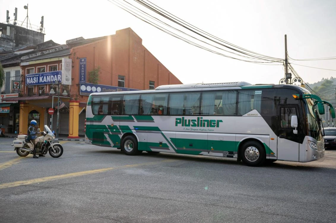 A bus carrying believed to be Myanmar migrants from Malaysia back to their homeland, is seen heading toward the Naval base in Lumut, outside Kuala Lumpur on Feb. 23, 2021. (AFP)