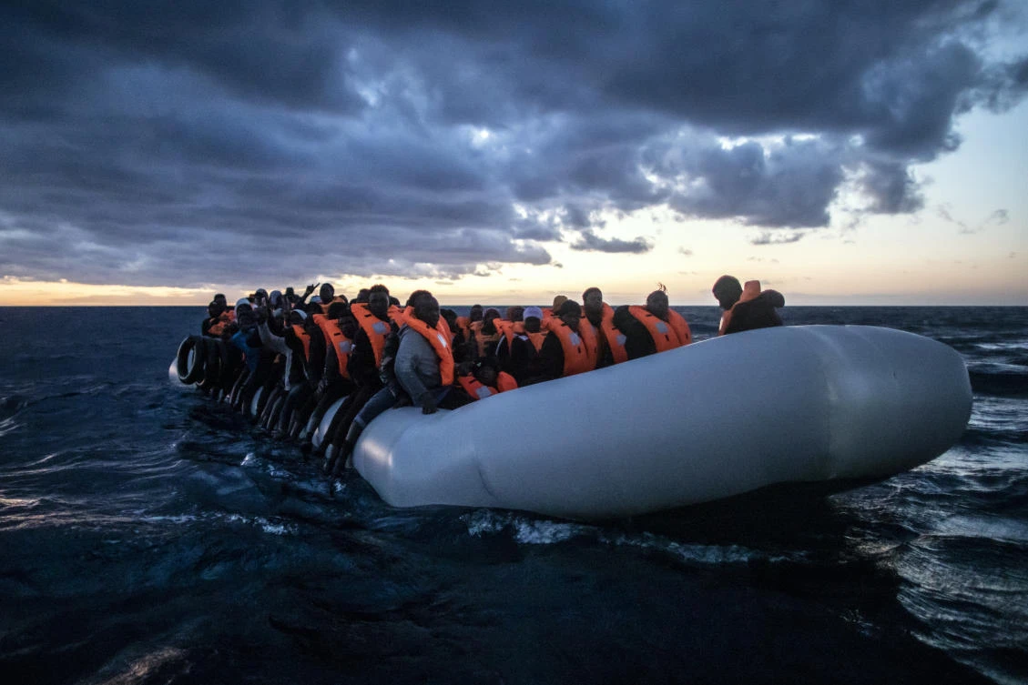Migrants and refugees from different African nationalities wait for assistance aboard a rubber boat as a rescue vessel approaches them in the Mediterranean Sea. (File/AP)
