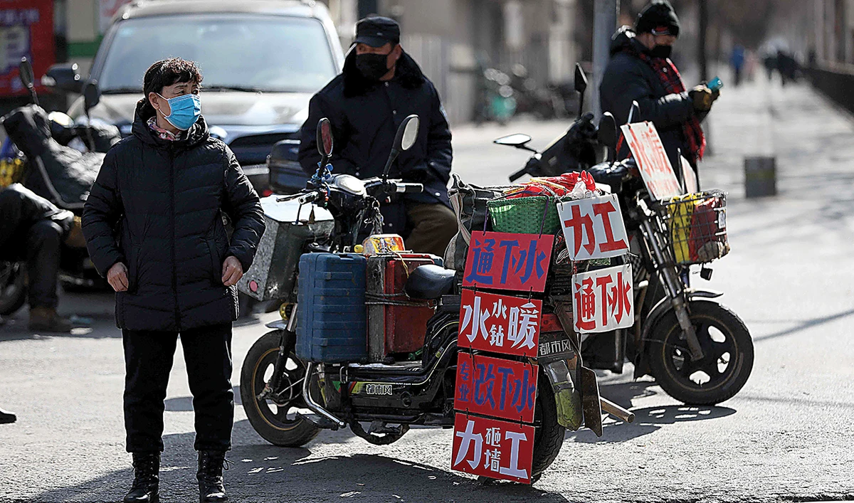 Workers stand next to signs advertising their work skills on a street as they wait to get hired in Shenyang, in northeastern China’s Liaoning province. (AFP)