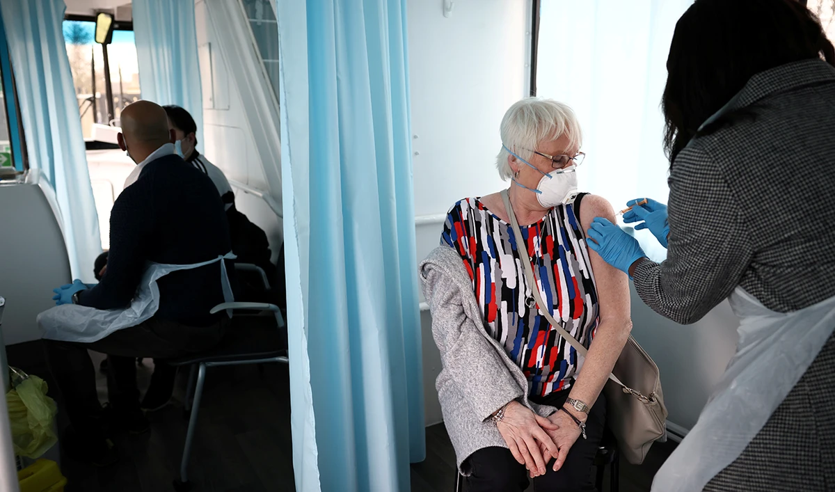 A woman receives a dose of the Oxford-AstraZeneca COVID-19 vaccine inside a bus modified into a mobile vaccination centre for the coronavirus disease (COVID-19), in Thamesmead, London. (Reuters)