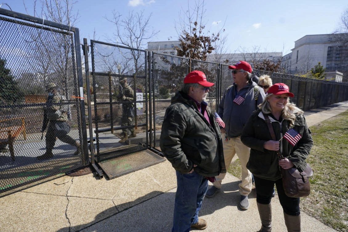 Supporters of former President Donald Trump stand outside of security fencing around the US Capitol in Washington D.C. as members of the national guard walk on the other side on March 4, 2021. (AP Photo/Alex Brandon)