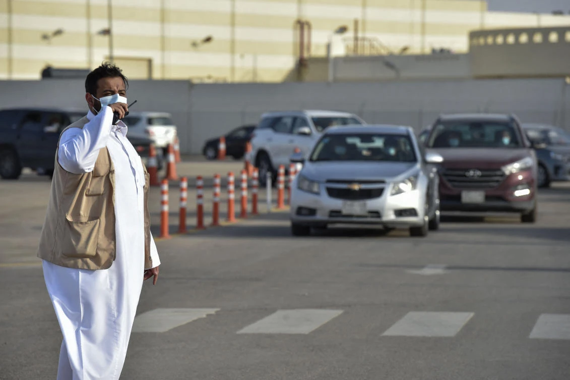 A member of staff organises the car queue as people arrive to receive a dose of the AstraZeneca COVID-19 vaccine at the first drive-through vaccination center in Riyadh, on March 4, 2021. (AFP)