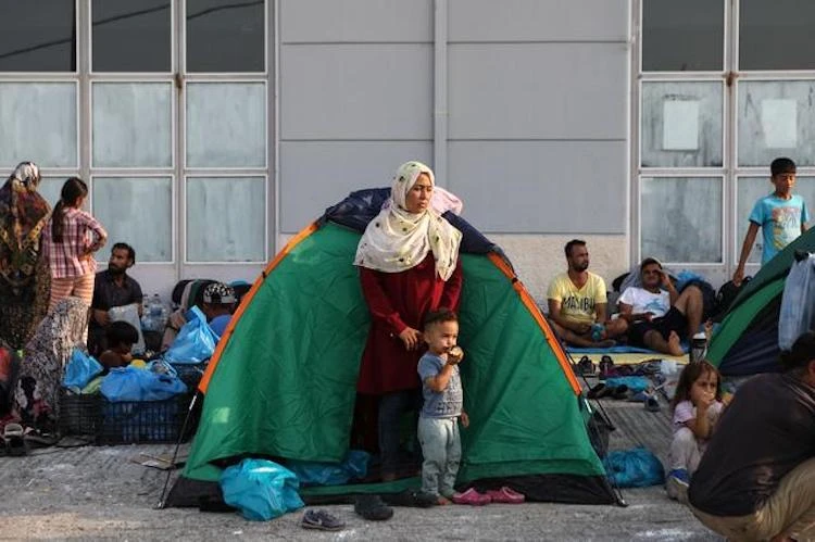 A woman and a child stand outside a tent as refugees and migrants from the destroyed Moria camp are sheltered at a temporary camp, on the island of Lesbos, Greece, Sept. 16, 2020. (Reuters)