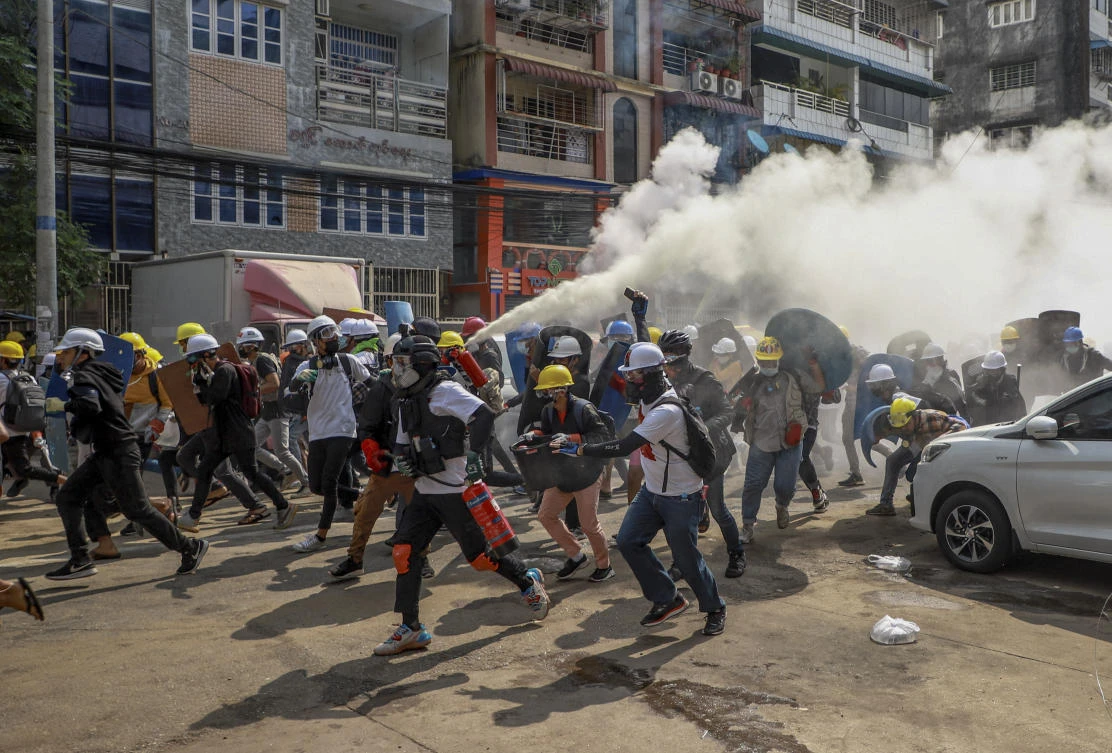 Anti-coup protesters run as one of them discharges a fire extinguisher to counter the impact of tear gas fired by riot policemen in Yangon, Myanmar, on March 3, 2021. (AP Photo)