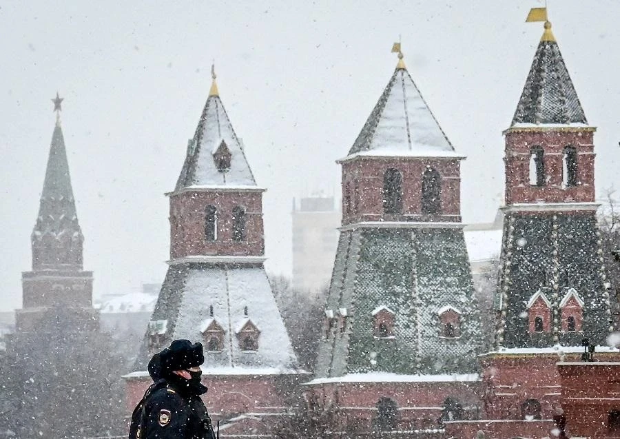 Two police officers wearing a face mask to protect against the Covid-19 disease cross a bridge under snow fall near the Kremlin in Moscow on March 8, 2021. (File/AFP)