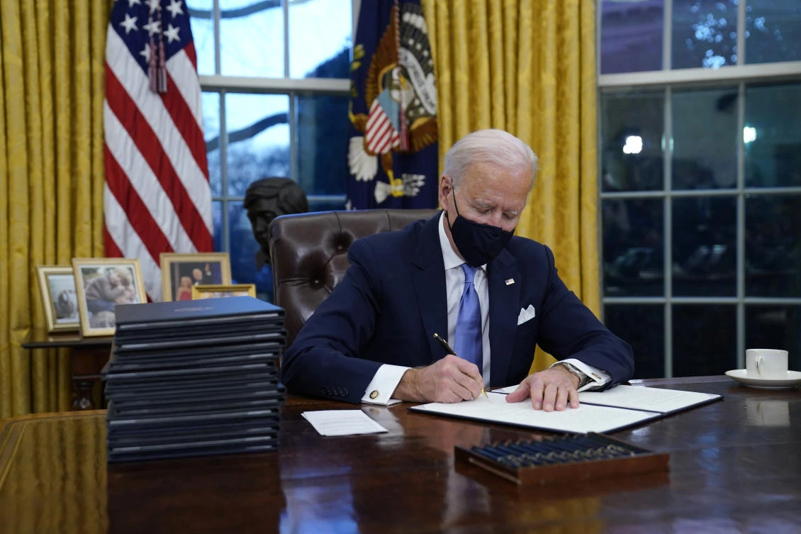 President Joe Biden signs his first executive order in the Oval Office of the White House in Washington. (File/AP)