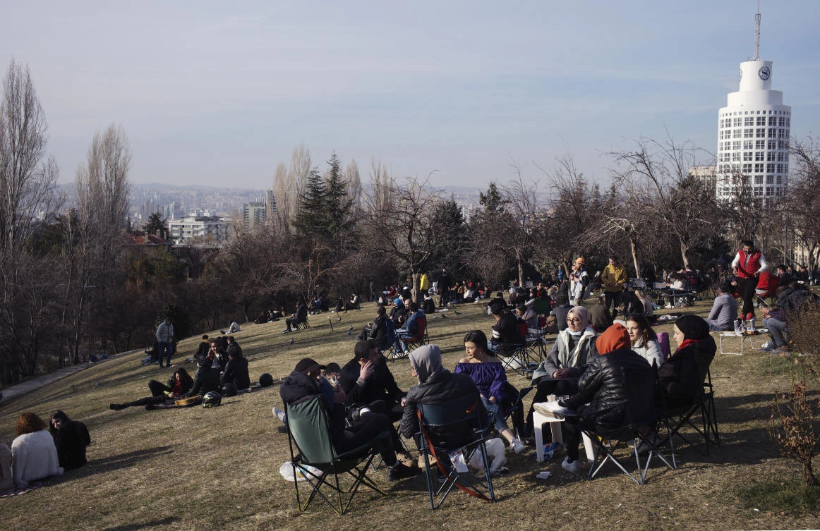 People sit in a park ignoring mask and social distancing rules, in Ankara, Turkey, Friday, March 12, 2021. (AP)