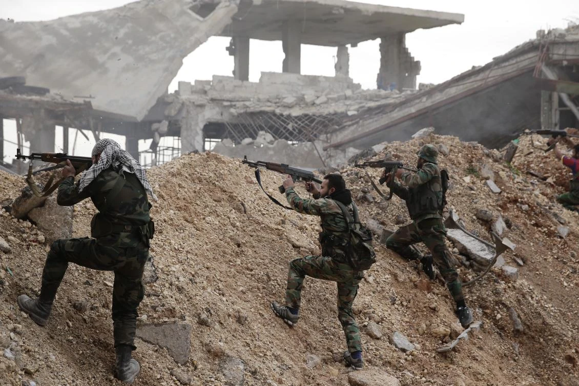 Syrian army soldiers fire their weapons during a battle with rebel fighters at the Ramouseh front line, east of Aleppo, Syria. (File/AP)
