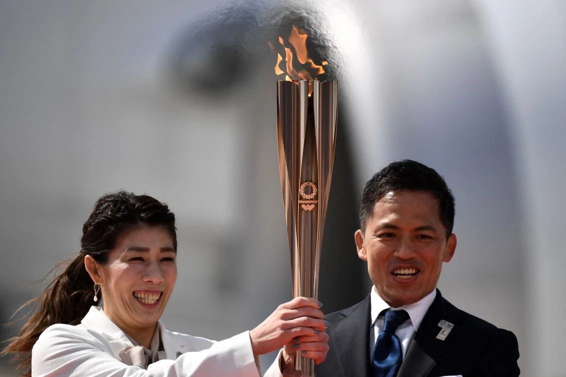 This file photo taken on March 20, 2020 shows Japanese three-time Olympic gold medallists Saori Yoshida (L) and Tadahiro Nomura (R) holding the Tokyo 2020 Olympic Torch. (AFP)
