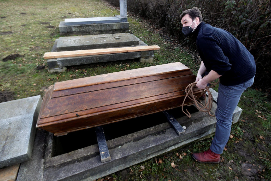 An actor Tomas Novotny secures an empty coffin at a training cemetery as a part of his re-qualification procedure amid the coronavirus pandemic in Prague March 9, 2021. (Reuters)