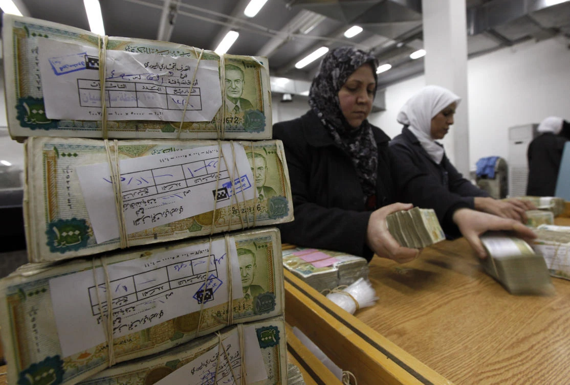 Employees stack money packets in Central Bank of Syria, whose President Bashar Assad granted financial stimulus to public sector workers and soldiers on Tuesday. (AP)