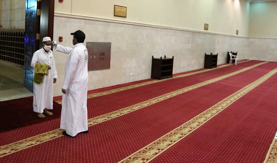 A volunteer checks the temperature of a man as he arrives to perform the dawn prayer at a mosque in the Saudi holy city of Makkah. (AFP file photo)