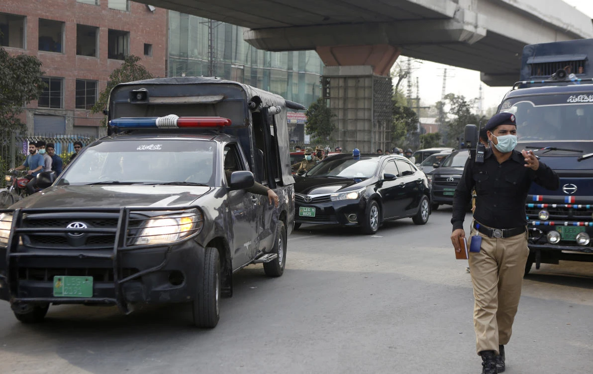 A police officer clears way for a convoy of an anti-terrorism court judge arriving at district jail, where the special court is set up for the trial of prime suspects in motorway gang-rape case, in Lahore, Pakistan. (AP)