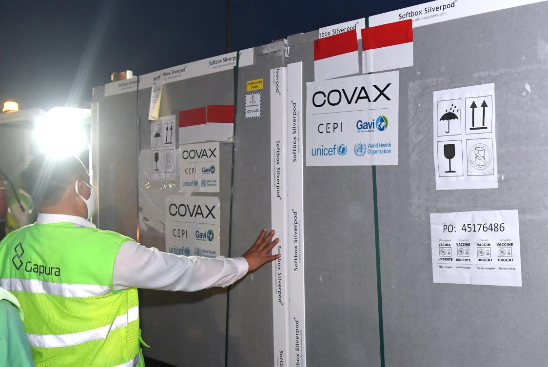 Workers unload containers containing AstraZeneca COVID-19 vaccine upon its arrival at Soekarno-Hatta International Airport on the outskirts of Jakarta, Indonesia. (Indonesian President Palace via AP)