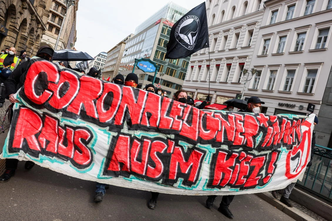 People hold a banner reading ‘Corona deniers out of the neighborhood’ as they attend a counter-protest during a rally against the German government’s restrictions following the coronavirus outbreak on March 20, 2021. (Reuters)