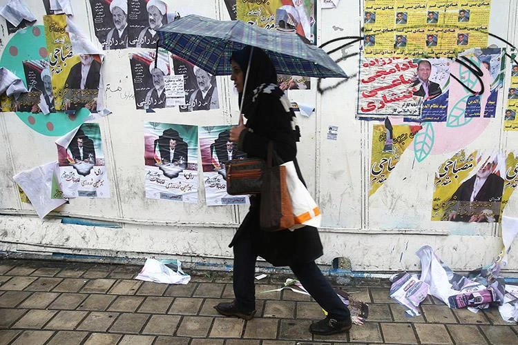 Iranian authorities are targeting journalists with arrests, detentions and legal action. Above, a woman passes campaign posters ahead of parliamentary elections, Tehran, Feb. 20, 2020. (Reuters)