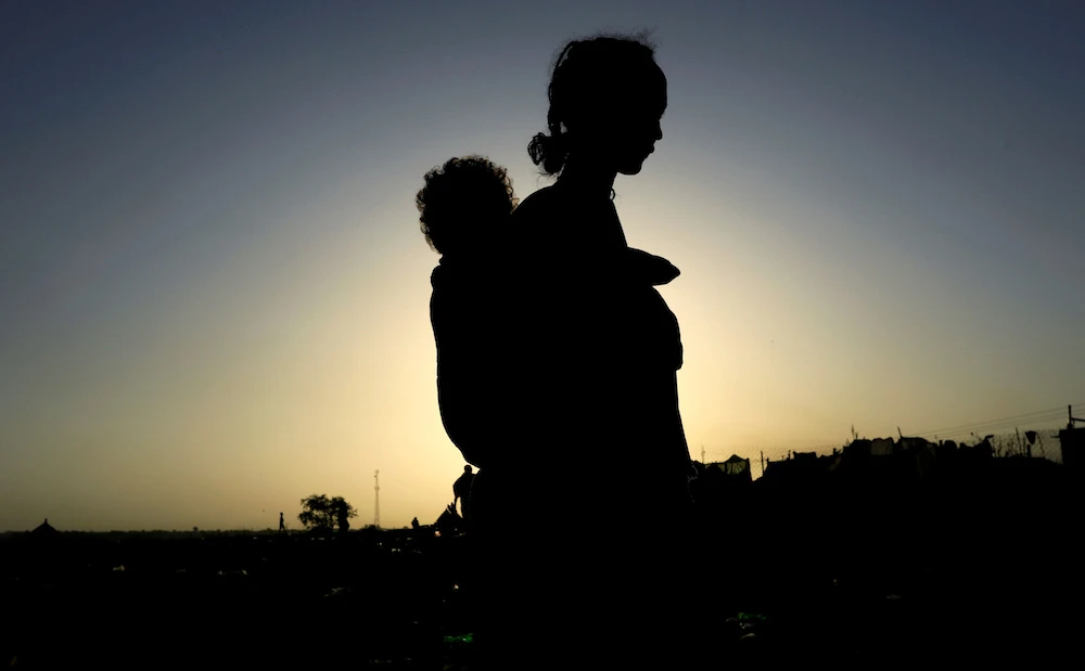 An Ethiopian woman who fled the ongoing fighting in Tigray region, carries her child near the Setit river on the Sudan-Ethiopia border in Hamdayet village in eastern Kassala state, Sudan. (File/Reuters)