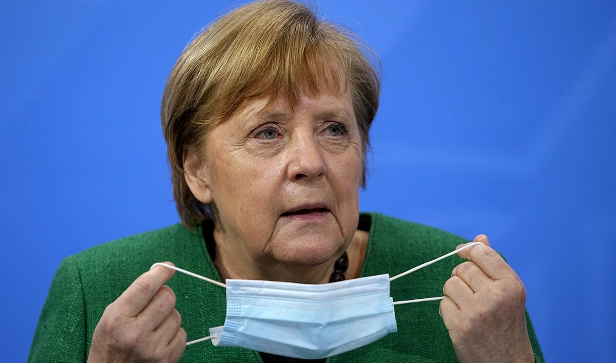 German Chancellor Angela Merkel pulls off her mask during a press conference in Berlin. (Reuters)