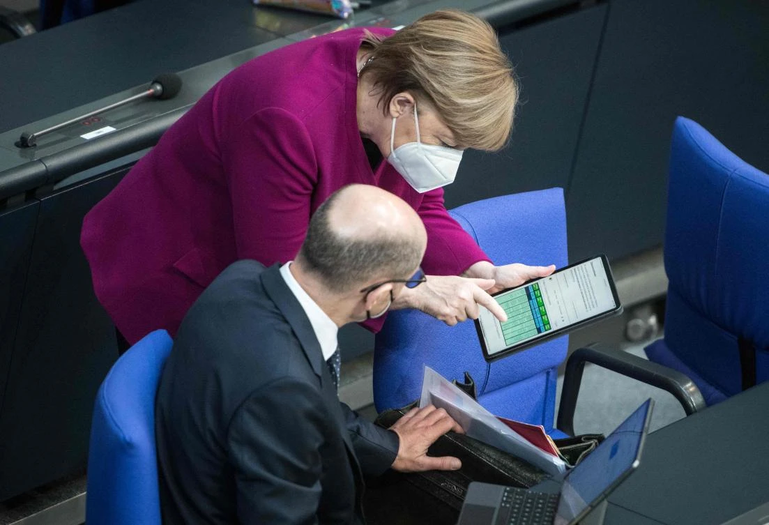 German Chancellor Angela Merkel shows plan for easing lockdown measures to German Finance Minister and Vice-Chancellor Olaf Scholz during a session at the lower house of parliament in Berlin ahead of an EU summit. (AFP)