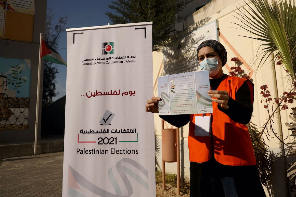 A Palestinian member of the Central Elections Commission displays an information leaflet following the opening of the first Voter Information and Registration Centre, Gaza City, Feb. 10, 2021. (AFP)
