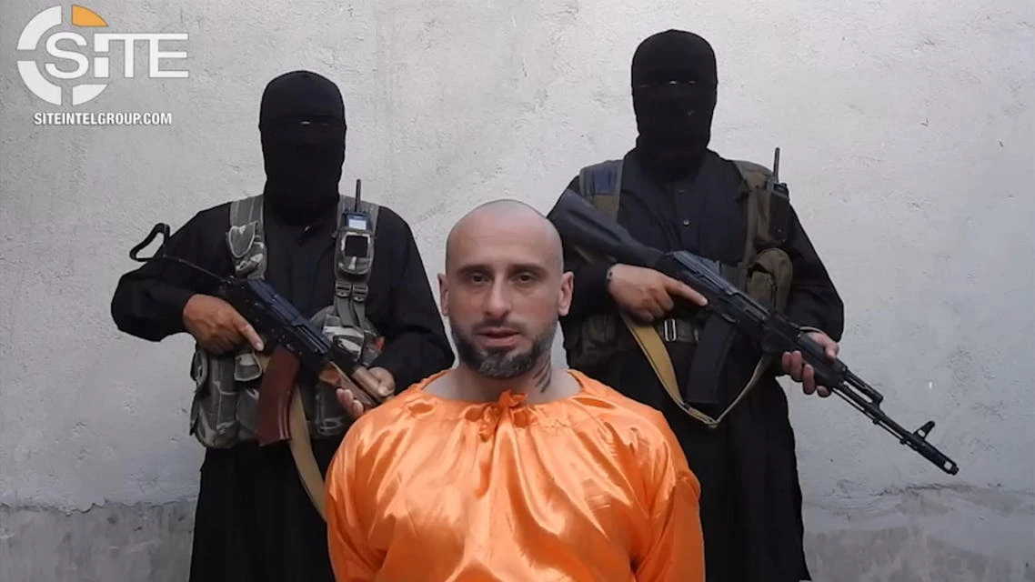 A video image released on July 31, 2018, courtesy of SITE Intelligence Group, shows Alessandro Sandrini appealing for his release as two armed men stand behind him at an unknown location in Syria. (AFP)