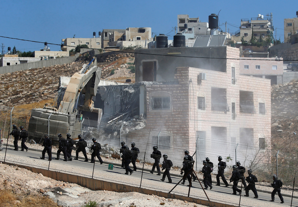 Israeli forces patrol as a Palestinian building is demolished in the village of Sur Baher, in the southeastern outskirts of East Jerusalem. (Reuters)
