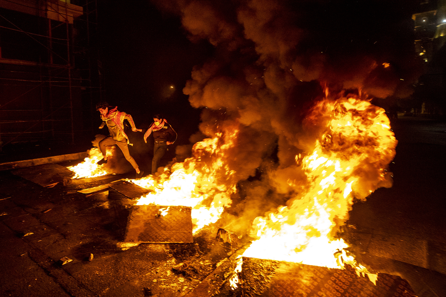 Protesters jump over burning tires that were set on fire to block a road, at Martyrs Square, in downtown Beirut, Lebanon, Saturday, March 6, 2021. (AP)