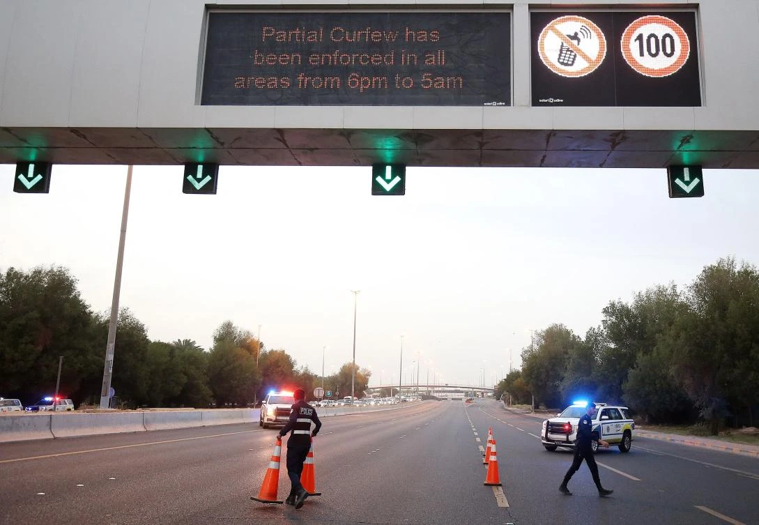 Kuwaiti policemen set up a check point on King Faisal road to control drivers during a curfew imposed by the authorities in a bid to stem the spread of the coronavirus, in Kuwait City, on April 1, 2021. (AFP)