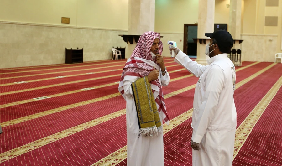 A volunteer checks the temperature of a man as he arrives to perform the dawn prayer at a mosque in the Saudi holy city of Makkah on June 21, 2020. (AFP)