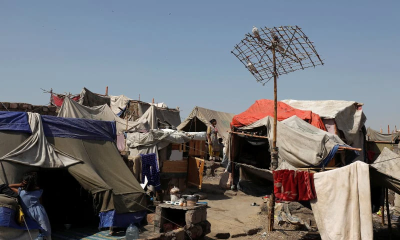 A mother and her son stand outside their tent in a slum, during a lockdown amid the outbreak of the coronavirus disease in Karachi. (Reuters)