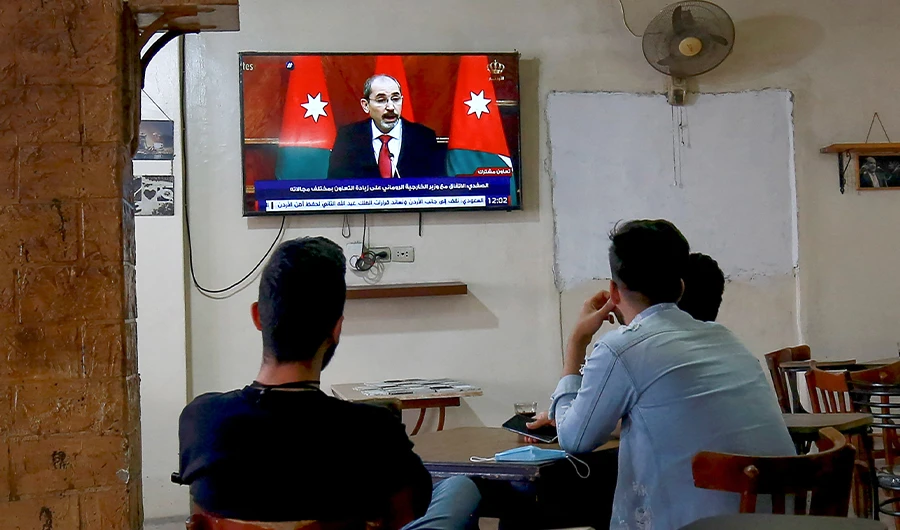 Jordanians follow the latest political developments in their country on a television set at a cafe in the capital Amman, on April 4, 2021. (AFP)