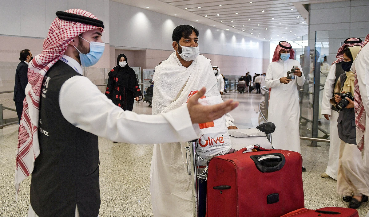 A mask-clad Pakistani traveller arriving in Saudi Arabia to perform Umrah pilgrimage is welcomed at the King Abdulaziz International Airport in the Red Sea coastal city of Jeddah on November 30, 2020, (AFP/File)