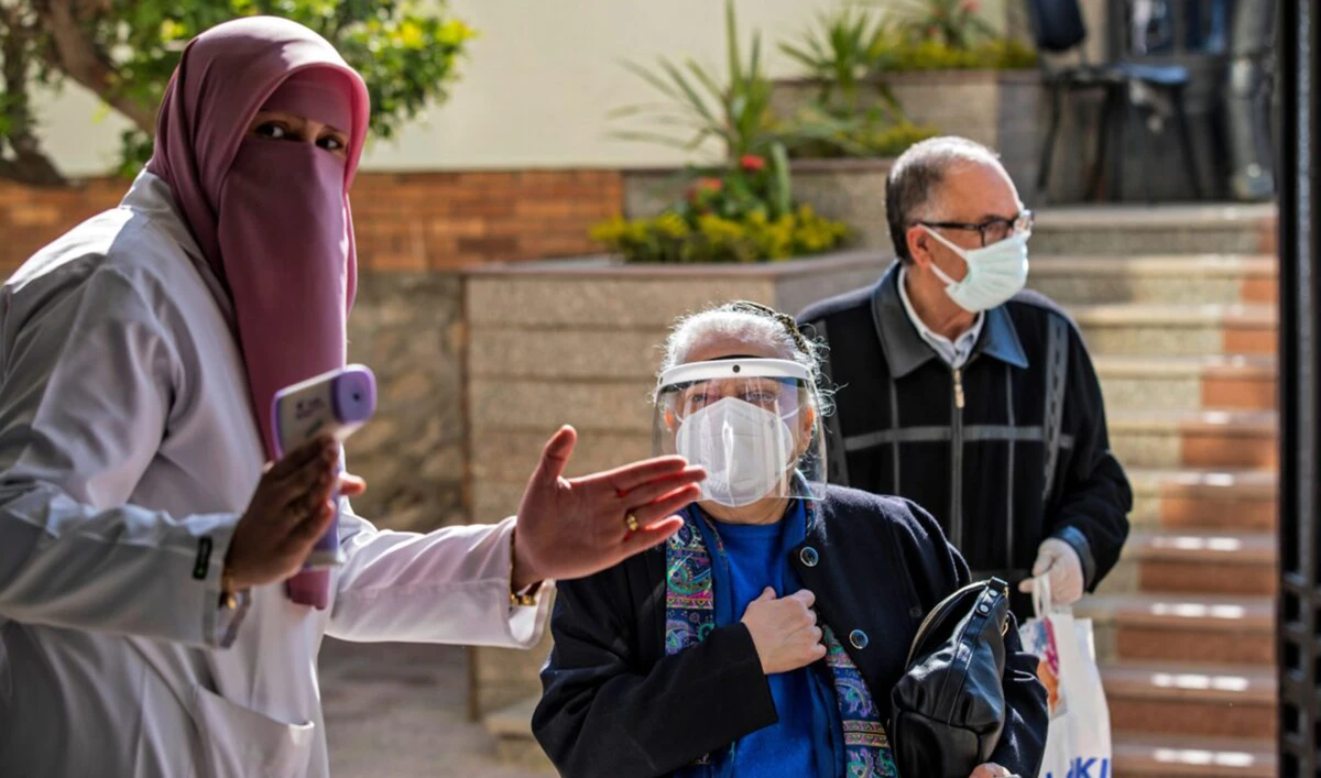 An Egyptian medical worker checks people's temperatures on the first day of vaccination against COVID-19 in Cairo, on March 4, 2021. (AFP)
