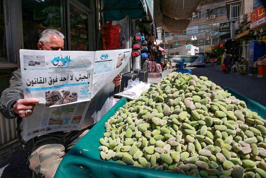 A Jordanian street vendor reads a local newspaper with a headline on its front page about the latest events in his country, in the capital Amman, on April 4, 2021. (AFP)