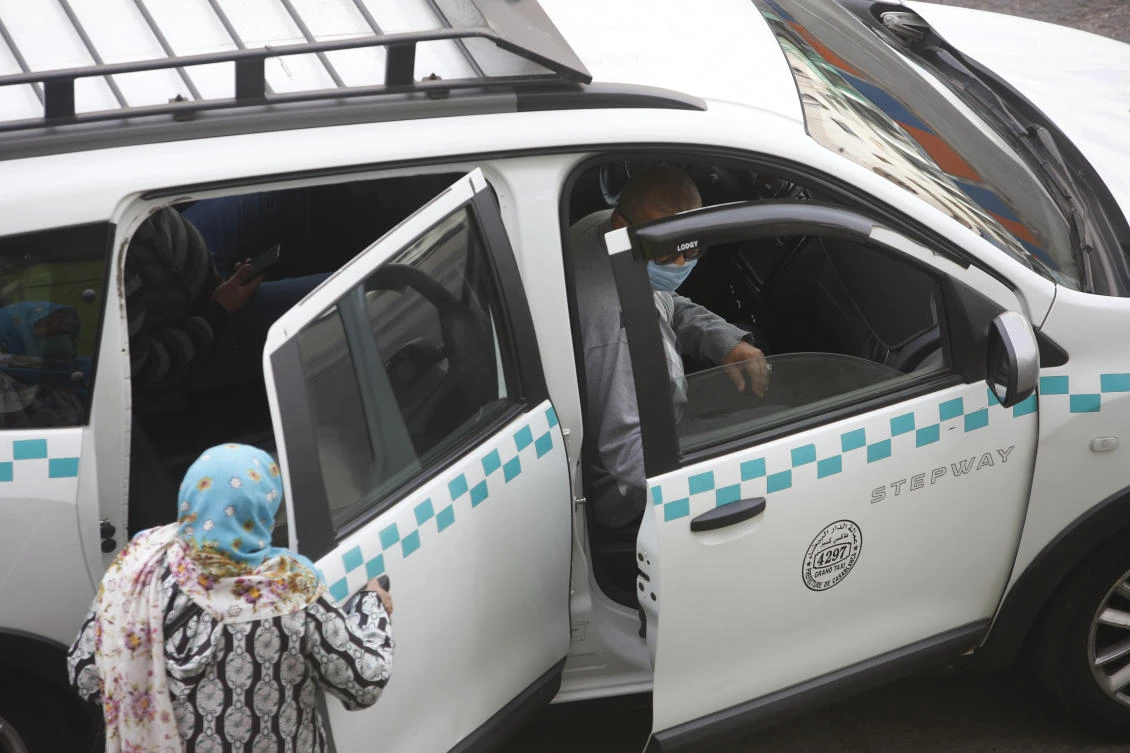 People wear face masks and take a taxi in Casablanca, Morocco, Tuesday, April 6, 2021. (AP Photo/Abdeljalil Bounhar)
