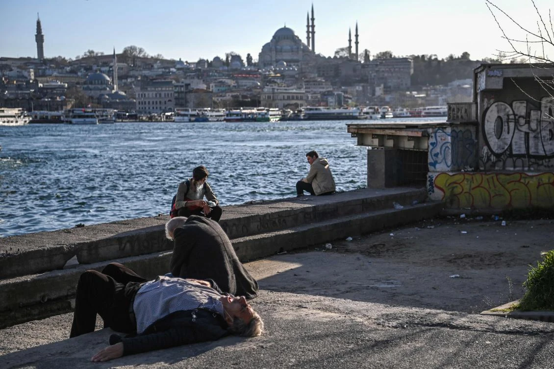 People sit near the Galata bridge, with the Hagia Sophia Holy Grand Mosque in background, during a sunset at Karakoy district in Istanbul, on April 7, 2021. (AFP)