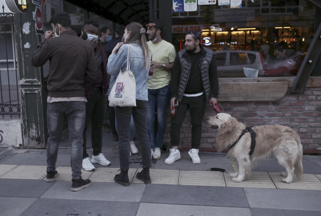 People, some ignoring masks and social distance rules, stand outside a cafe after restaurants and cafes in Ankara, Turkey on April 8, 2021. (AP)