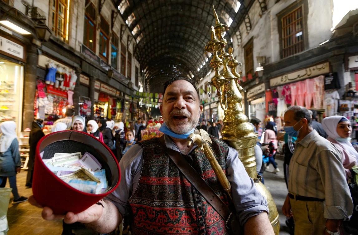 Ishaaq Kremed, a tamarind juice seller, calls on customers in the covered Hamidiyah market in the old part of the capital Damascus on April 8, 2021. (AFP)