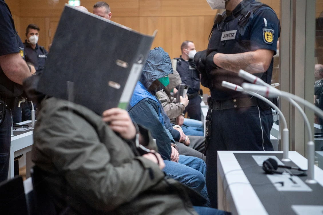 A defendant covers his face at the beginning of a trial against 12 Germans charged with belonging to a far-right organization at a higher regional court in Stuttgart, Germany, April 13, 2021. (Reuters)