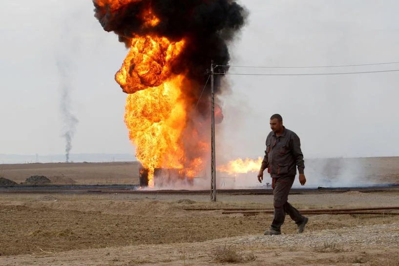 An employee walks as oil wells burn inside the Khabbaz oilfield after they were bombed on the outskirts of Kirkuk, Iraq December 9, 2020. (Reuters)