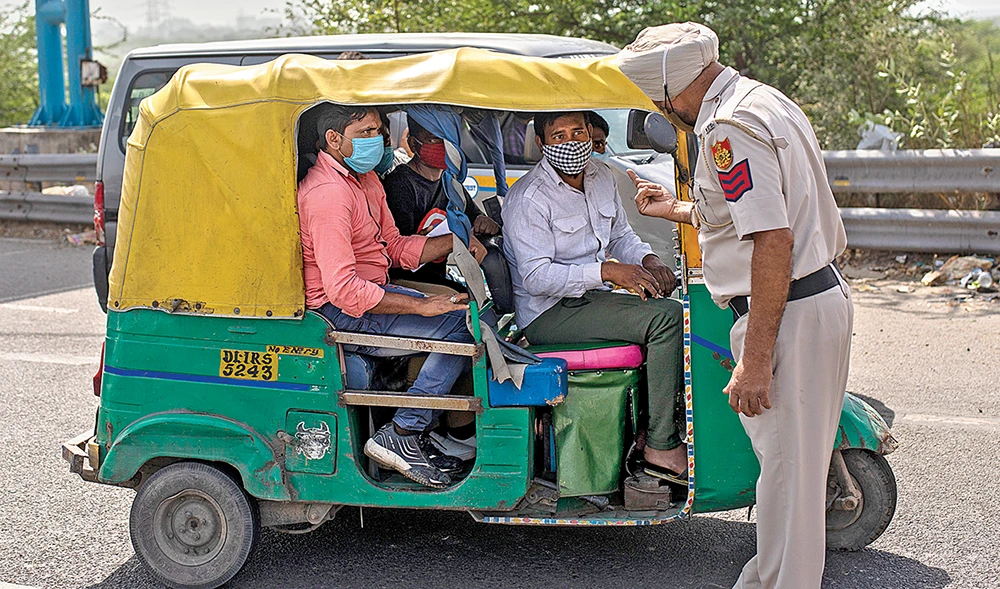 A police officer stops an auto-rickshaw at a checkpoint on Saturday during a lockdown in New Delhi. (AP)