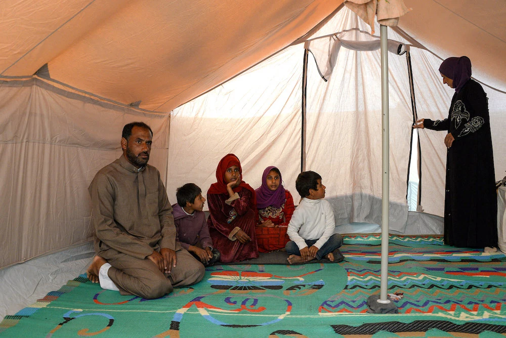A picture taken on November 12, 2018, shows Maareb (3rd-L) sitting with her family in their tent at a (UNHCR) camp for displaced people in Hammam al-Alil, south of the northern Iraqi city of Mosul. (AFP/File Photo)