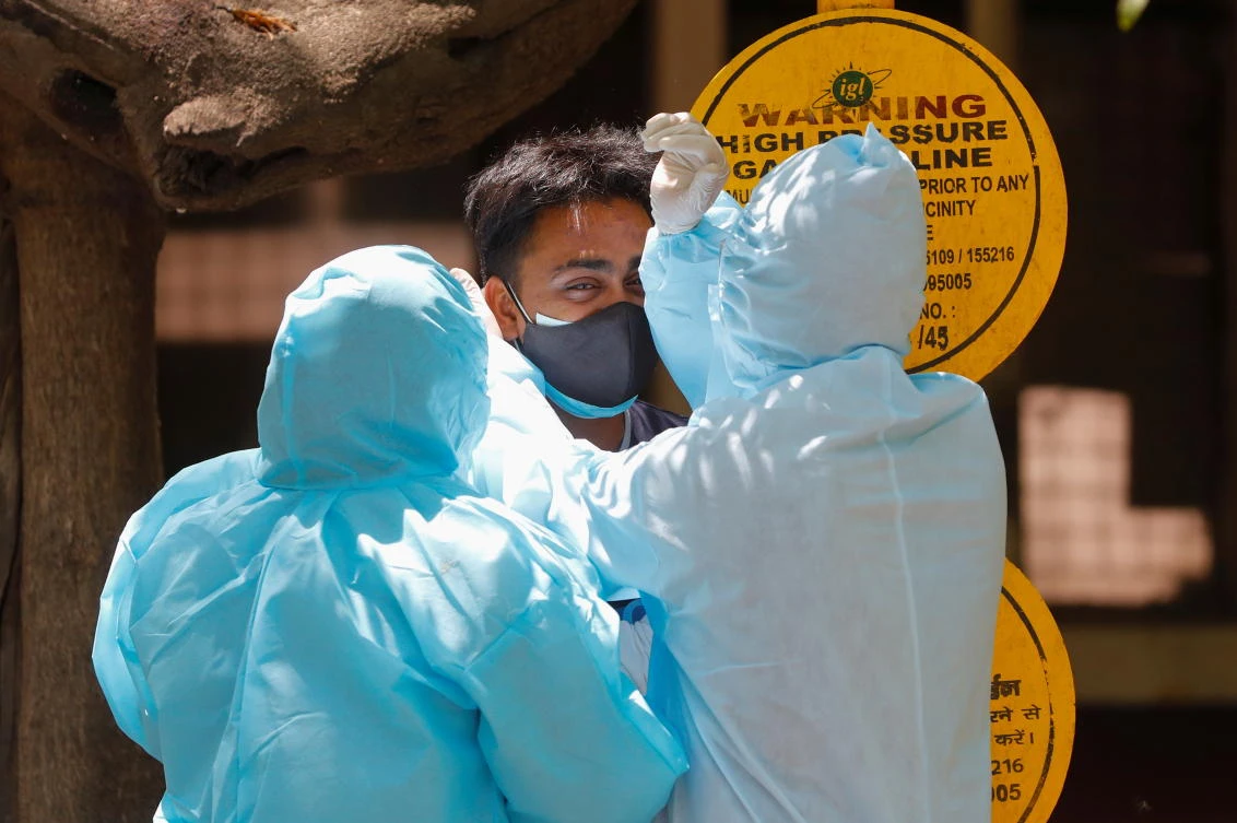 People wearing personal protective equipment (PPE) console a relative of a person who died due to the coronavirus disease (COVID-19), outside the Guru Teg Bahadur hospital, in New Delhi, India, April 24, 2021. (Reuters)