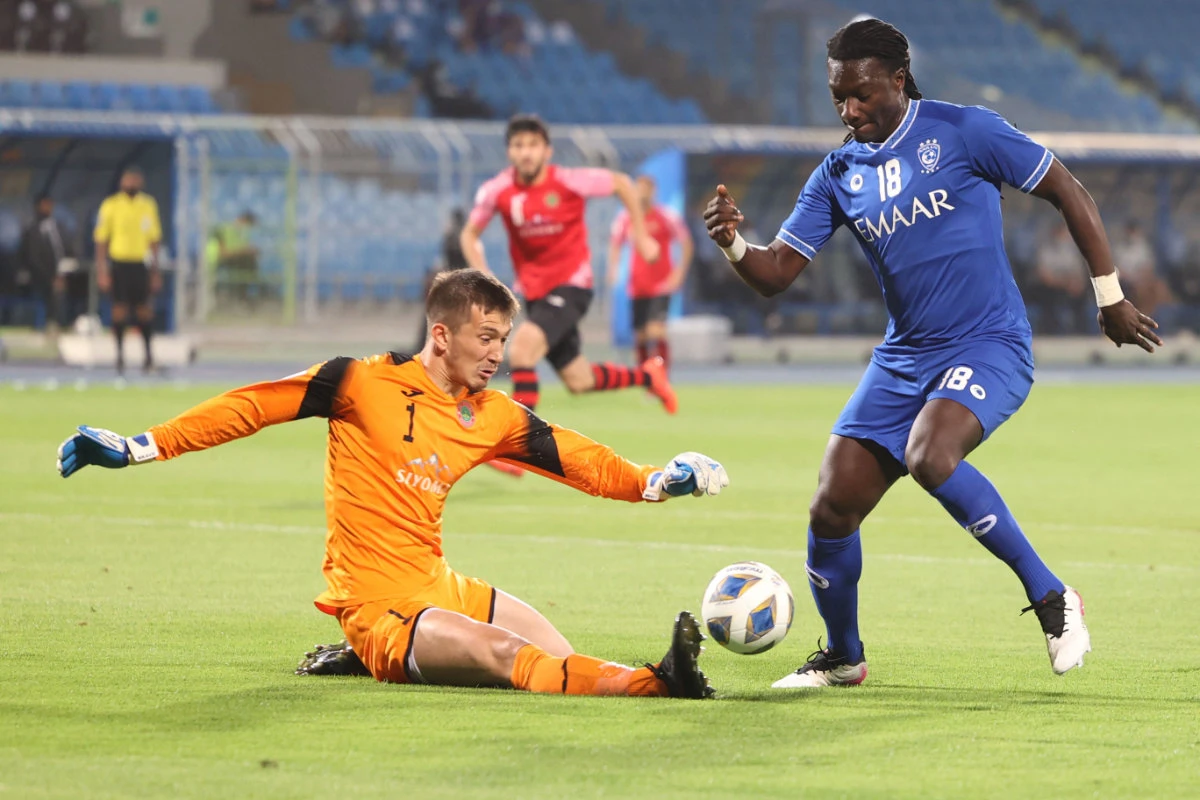 Istiklol's goalkeeper Rustam Yatimov (L) vies for the ball with Hilal's forward Bafetimbi Gomis during their AFC Champions League group A match in Riyadh on April 21, 2021. (AFP / Fayez Nureldine)
